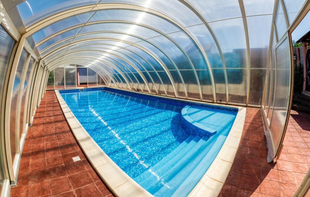 Covered summer pool with a blue tile. The covered area of the outdoor pool for hotel. Water retains heat longer and protect from the wind.